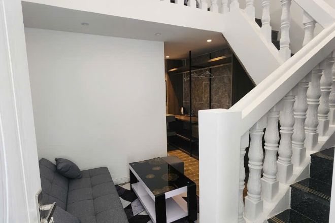 Un interno moderno con una scala, un angolo salotto con un divano e un tavolino, e scorcio di una zona pranzo.