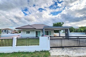 A single-story house with a covered porch, a fenced yard, and a clear sky. - Pool Villa - Phetchabun (Phetchabun)