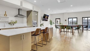 A modern kitchen with a white countertop, stainless steel appliances, and a large island with bar stools. - Charming 1-bed loft, downtown Cleveland with GYM, Rooftop deck, Fire pit, games (Cleveland)