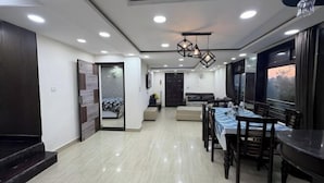 A spacious living area with a dining table, kitchen, and a large window. - Rudhraksh Villa 4BR- Perfect Vacay Villa (Mussoorie)