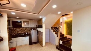 A compact kitchen with modern appliances, a built-in oven, and a small refrigerator. - Rudhraksh Villa 4BR- Perfect Vacay Villa (Mussoorie)