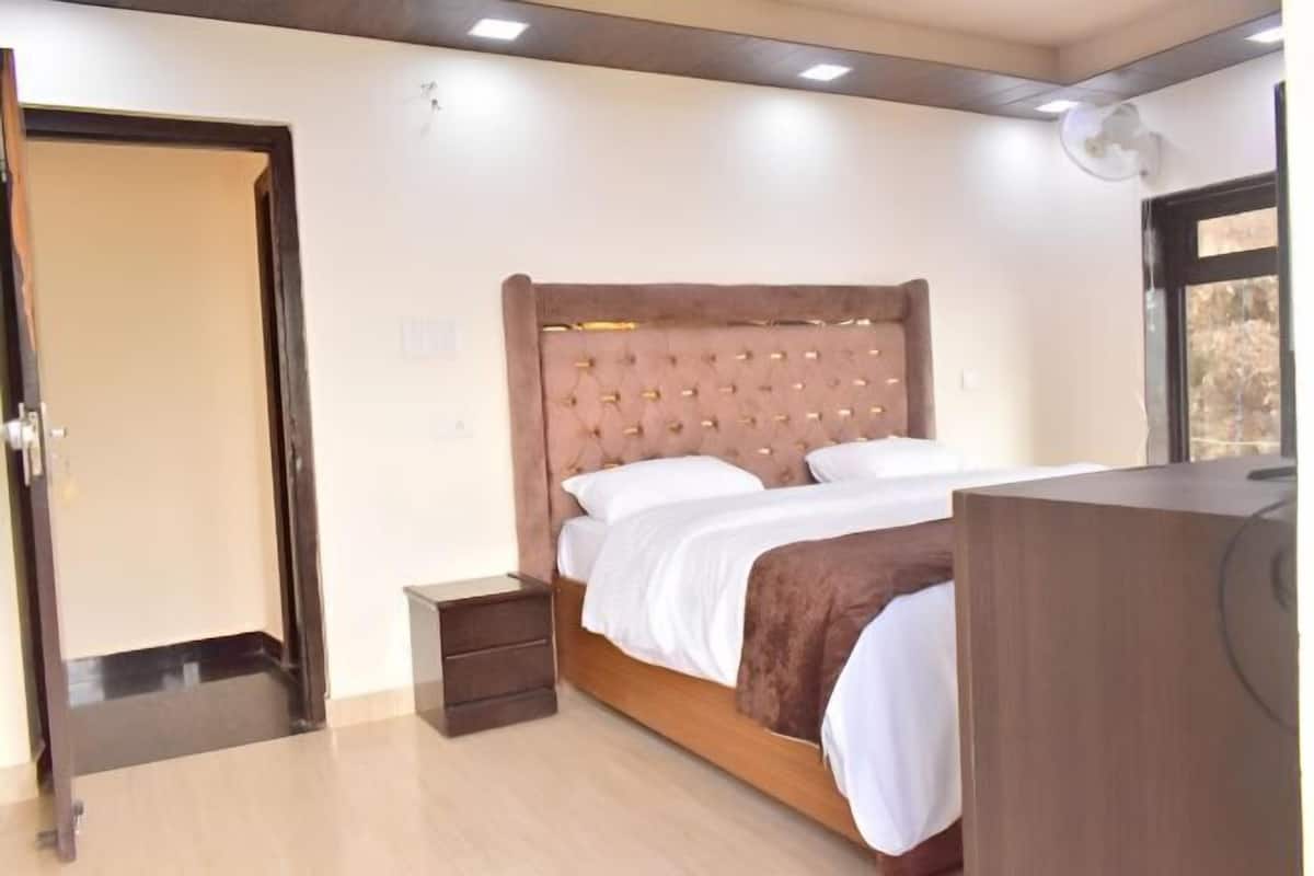 A bedroom with a bed, bedside tables, a dresser, and a door.