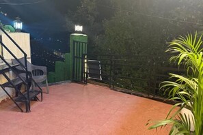 A rooftop terrace with a red floor, a green gate, and a railing. - Rudhraksh Villa 4BR- Perfect Vacay Villa (Mussoorie)