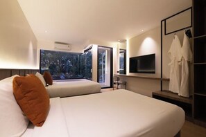 A modern hotel room with a large bed, a seating area, a TV, and a view of the outdoors. - P Villas Patong (Phuket)