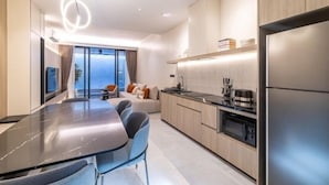 A modern kitchen with a dining area, stainless steel appliances, and a view of the ocean. - P Villas Patong (Phuket)