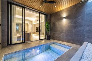 A modern indoor pool area with a clear view of the adjacent living space through glass doors. - P Villas Patong (Phuket)