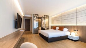 A modern hotel room with a bed, bedside table, and a TV mounted on the wall. - P Villas Patong (Phuket)