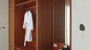 Een houten garderobe met een badjas, een spiegel en een kruk.