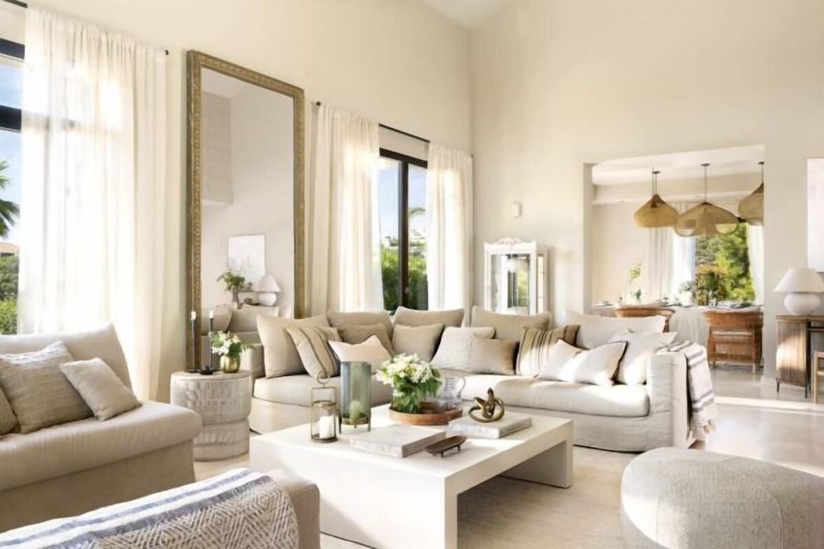 A spacious living room with a large sofa set, a coffee table, and a dining area.