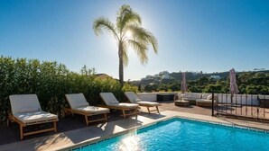 A rooftop pool with lounge chairs and a palm tree. - All About La Boheme (Benahavis)