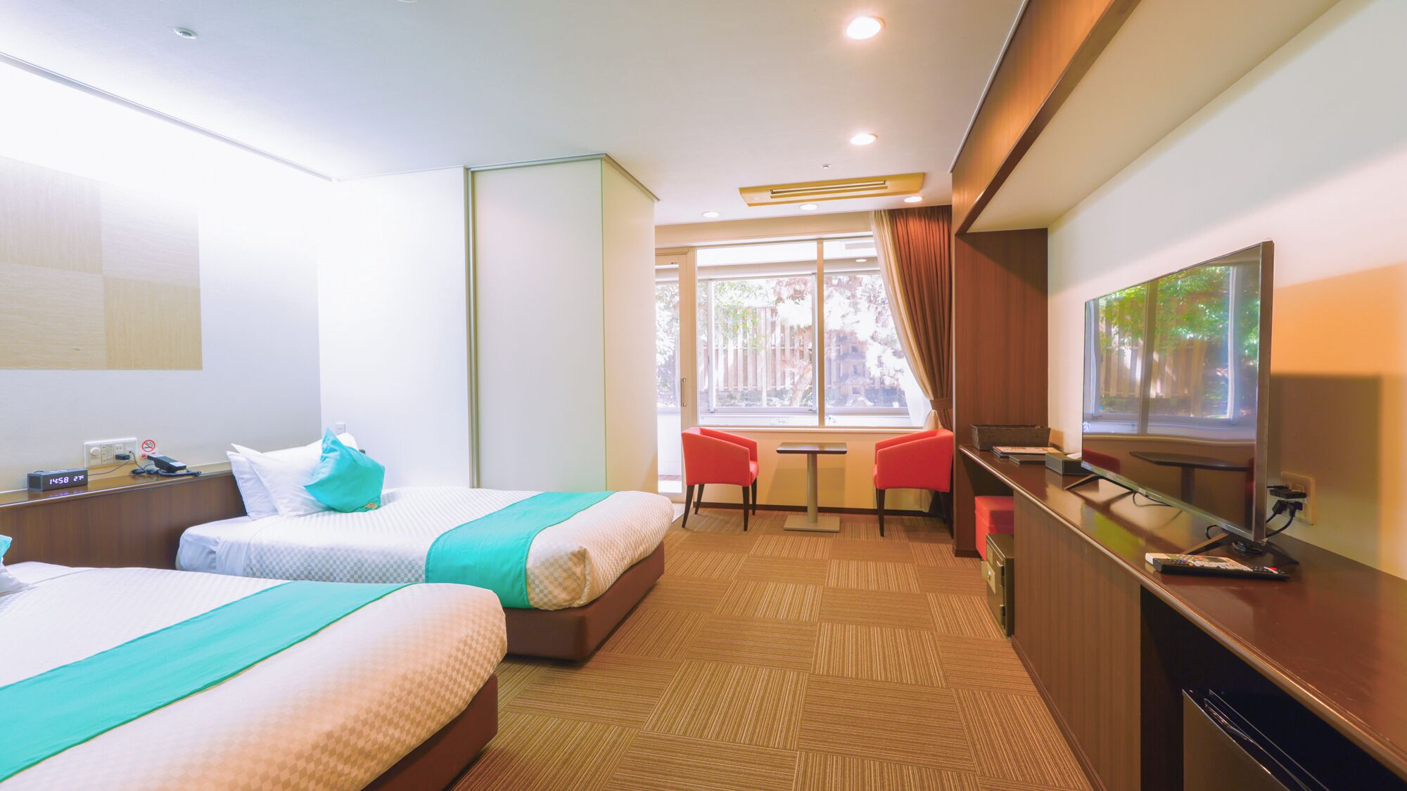 A hotel room with two beds, a desk, a TV, and a window with a view.