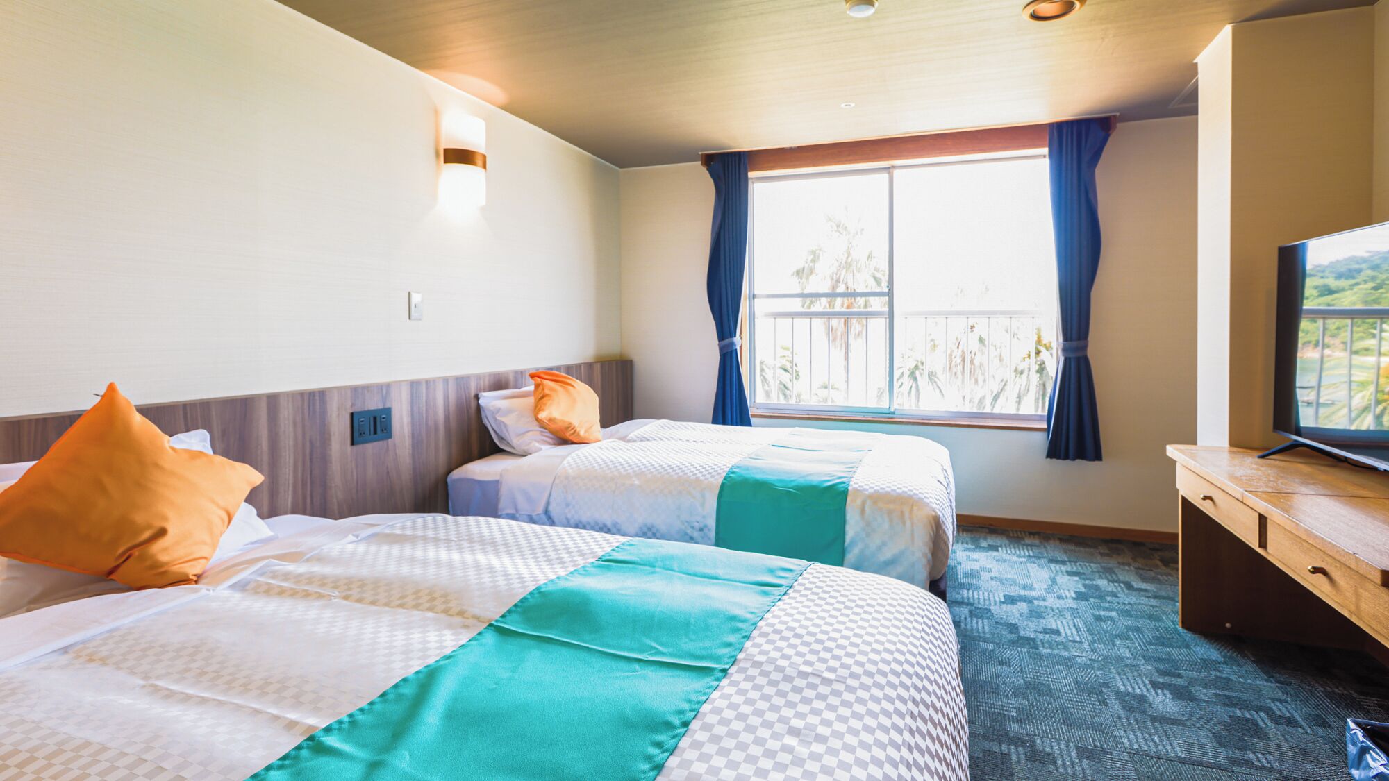 A hotel room with two beds, a television, and a window with curtains.