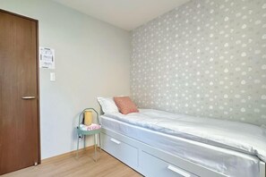 A bedroom with a single bed, a chair, a small table, and a door. - EI・RIN (Osaka)