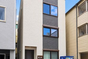 A multi-story residential building with a flat facade, large windows, and a door with a sign above it. - EI・RIN (Osaka)
