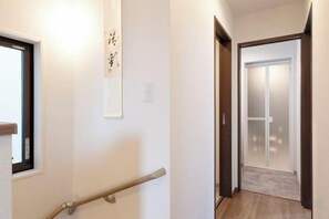 A hallway with a handrail, a door with frosted glass panels, and a wall-mounted sign. - EI・RIN (Osaka)