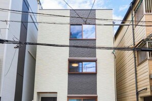 A multi-story building with a modern facade, multiple windows, and visible electrical wires. - EI・RIN (Osaka)