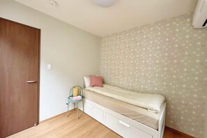 A bedroom with a single bed, a chair, a wardrobe, and a patterned wall. - EI・RIN (Osaka)