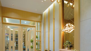 A hotel lobby with a modern design, featuring a large glass door entrance, a neon sign, and a decorative light fixture. - Hotel Saubhagya Ahmedabad (Ahmedabad)