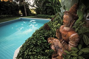 A statue by a pool with lush greenery. - Pa Sak Tong (Chiang Rai)