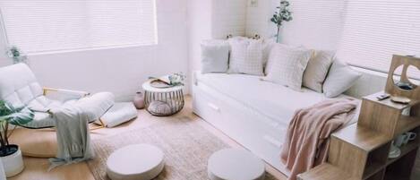 A bedroom with a bed, a chair, a round table, and a bedside table.