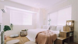 Une chambre à coucher moderne avec un lit, des tables de chevet, une petite table ronde et une plante en pot.