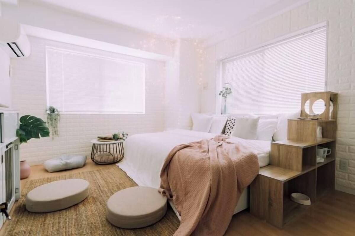 Une chambre à coucher moderne avec un lit, des tables de chevet, une petite table ronde et une plante en pot.