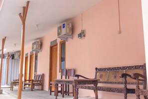 A corridor with wooden furniture and air conditioning units. - Wahyu Putri House Yogyakarta (Kraton)