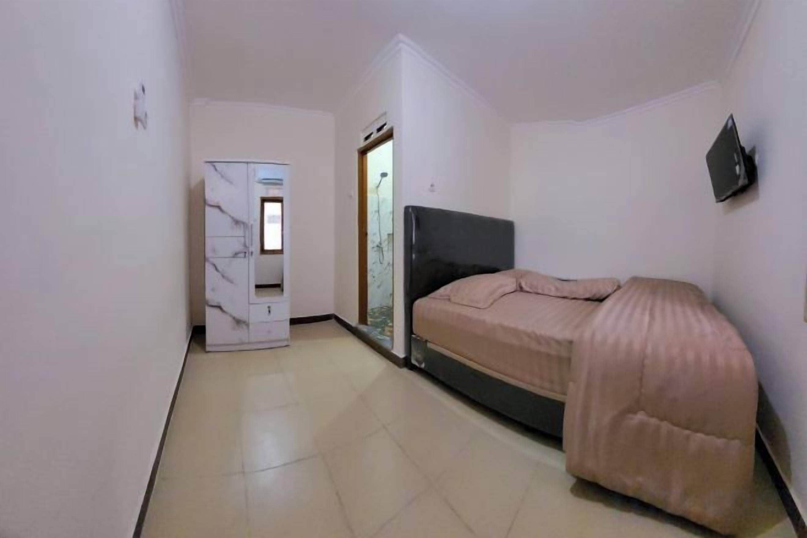 A small bedroom with a bed, a wardrobe, and a shower area.