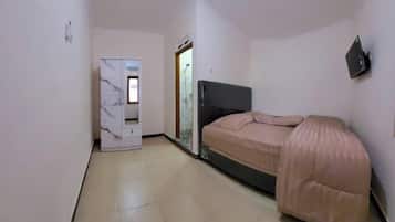 A small bedroom with a bed, a wardrobe, and a shower area.