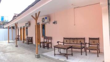 A covered outdoor seating area with wooden furniture and a tiled floor.