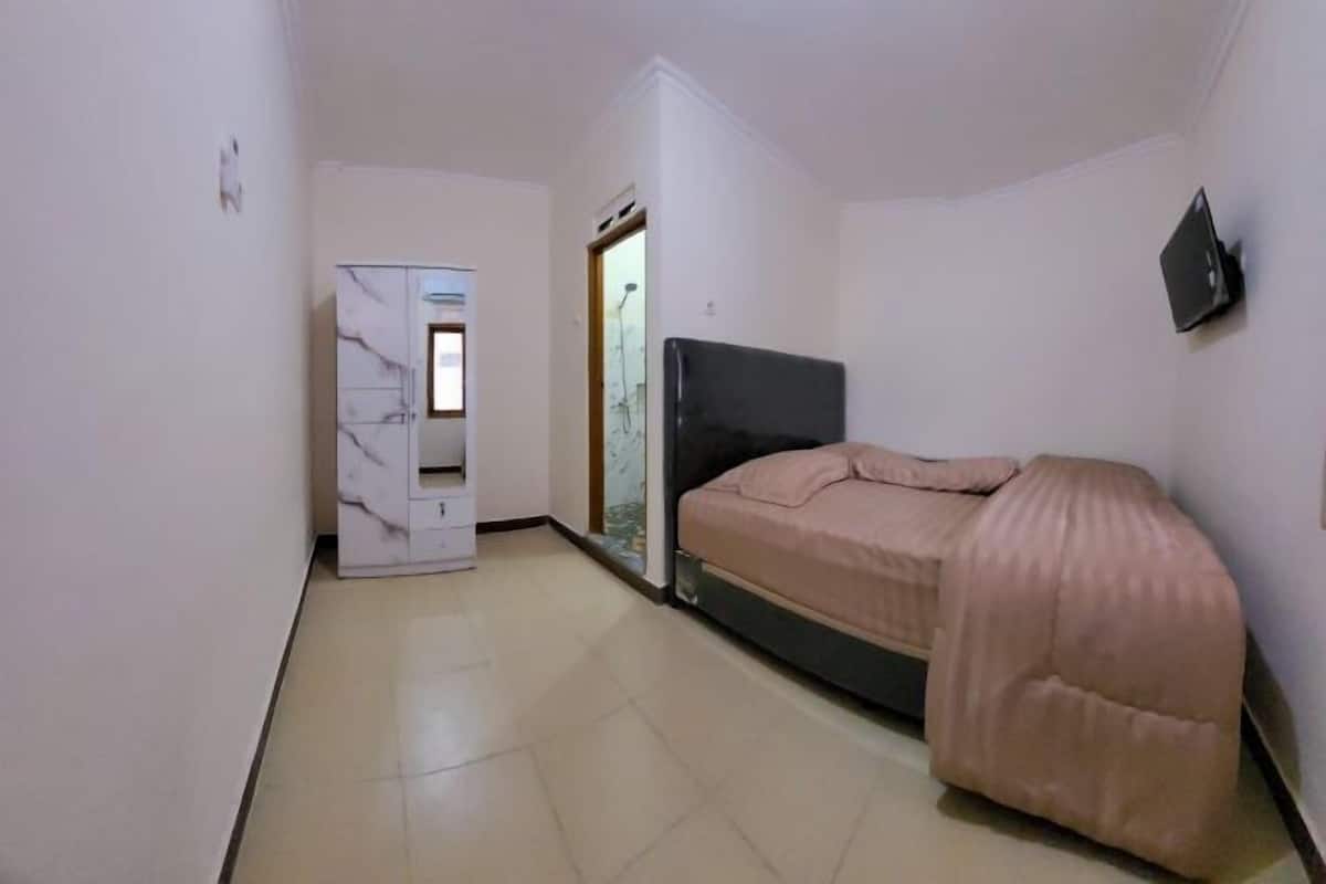 A bedroom with a bed, a wardrobe, and a door leading to another room.