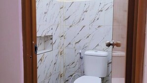Egy fürdőszoba, amelyben WC, márványburkolat és egy ajtó található.