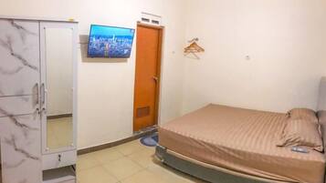 A bedroom with a bed, a wardrobe, a television, and a door.