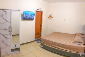 A bedroom with a bed, a wardrobe, a television, and a door. - Wahyu Putri House Yogyakarta (Kraton)