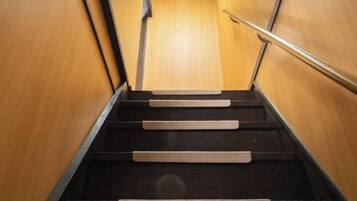 A set of wooden steps leading upwards, with a metal handrail on the right.