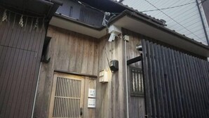 A wooden building with a barred entrance, a small window, and a metal gate. - KIRAKU･SHIMIZU (Kyoto)