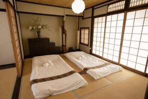 A traditional Japanese room with tatami flooring, two beds with white bedding, a wooden dresser, and a window with a view. - KIRAKU･SHIMIZU (Kyoto)
