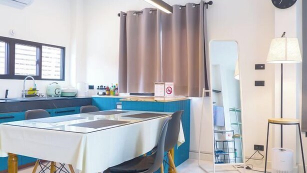 A modern kitchen with a dining area, including a table, chairs, and a counter with kitchen appliances. - TT63/2 cozy private house near the city (Chiang Mai)