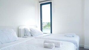 A hotel room with two beds, white linens, a window with a view, and a nightstand with a lamp. - TT63/2 cozy private house near the city (Chiang Mai)