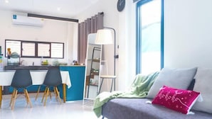 A modern living room with a sofa, a dining area with chairs, a kitchen area, and a large window with curtains. - TT63/2 cozy private house near the city (Chiang Mai)