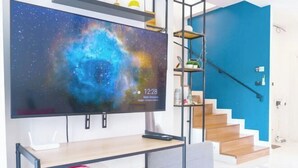 A modern living room with a large flat-screen TV, a wooden table, a grey sofa, and a blue staircase. - TT63/2 cozy private house near the city (Chiang Mai)
