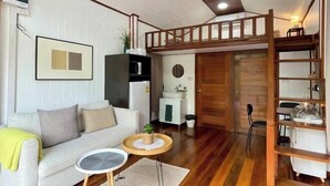 A compact living space with a loft bed, a sofa, a small dining table, and a kitchenette. - Anna River Home A3 (Bangkok)