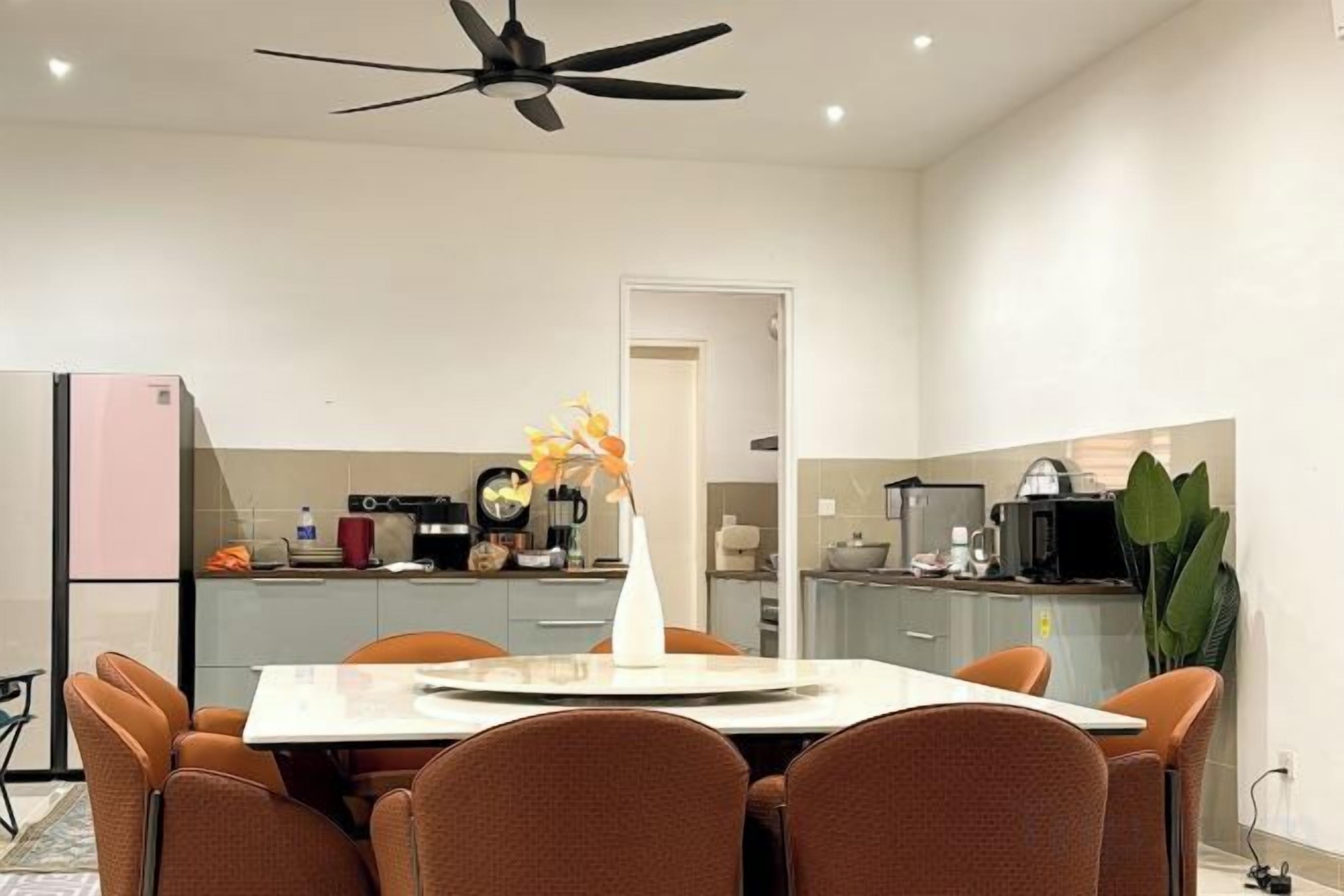 A modern kitchen with a dining area, a ceiling fan, and a refrigerator.