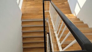 A wooden staircase with white railings and a black handrail.