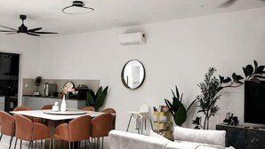 A modern dining area with a round table, chairs, and a ceiling fan.