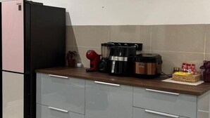 A kitchen with a refrigerator, coffee maker, and a kettle on the counter.