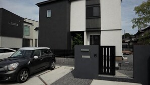 Ein modernes, zweistöckiges Gebäude mit Schwarz-Weiß-Fassade, einem befahrbaren Tor und einem abgestellten Auto.