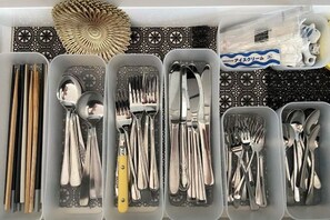 A storage unit with compartments containing various utensils, including forks, spoons, and chopsticks. - star residence (Inzai)