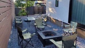 Eine Außenpatio-Terrasse mit Feuerstelle, Klappstühlen und einem Tisch.