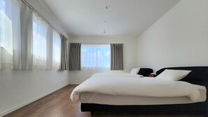 Ein Schlafzimmer mit einem Bett, einem Fenster mit Vorhängen und Holzboden.